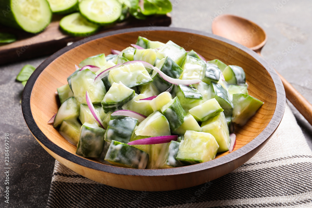 Wooden dish with fresh creamy cucumber salad served on table