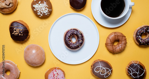 Overhead view of variety of donuts with coffee cup