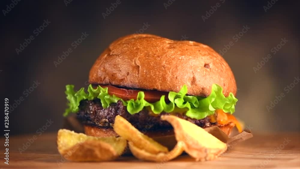 Hamburger with fries rotated on dark background. Cheeseburger served with french fries. Slow motion. 4K UHD video footage. 3840X2160 Hamburger with fries rotated on dark background. Cheeseburger served with french fries. Slow motion. 4K UHD video footage. 3840X2160