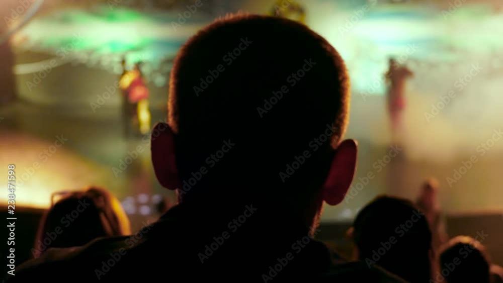 Video from the back silhouette man sitting looking performance or presentation in the theater light audience concert hall stage play abstract audience slow motion