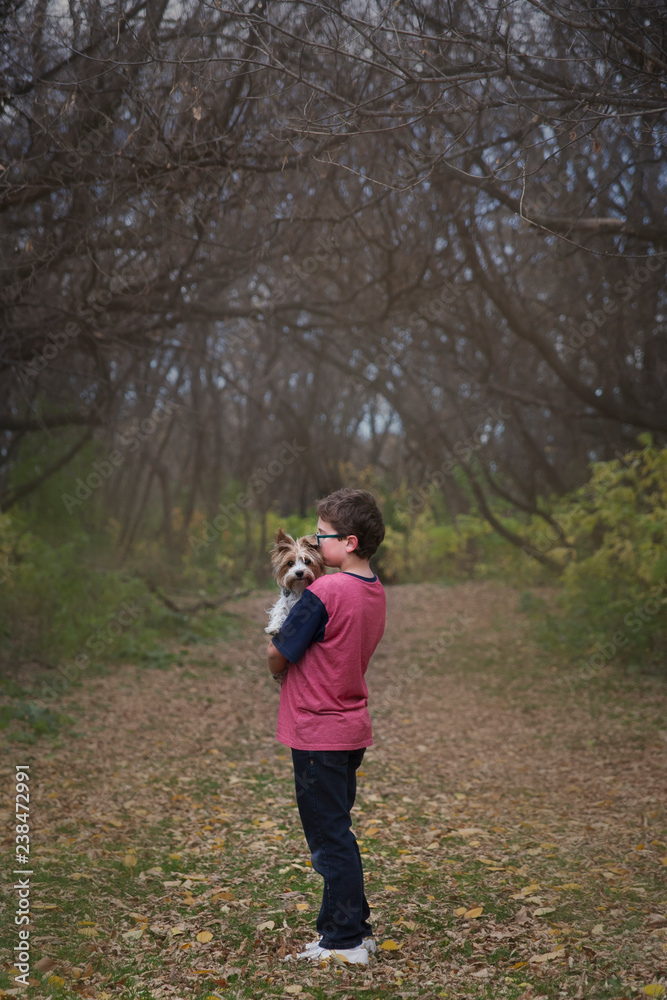 Boy carrying dog while standing on grassy field at park Boy carrying dog while standing on grassy field at park