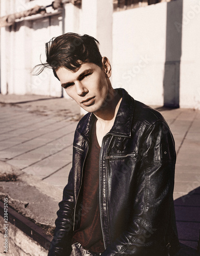 Portrait of young man wearing  leather jacket sitting outdoors photo