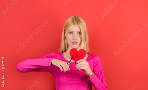 Heart, woman, sadness. Sad woman cuts with scissors red paper heart to pieces. Concept of divorce, parting, separation, end of love. Girl with scissors cutting heart. Female cuts red Valentines heart.