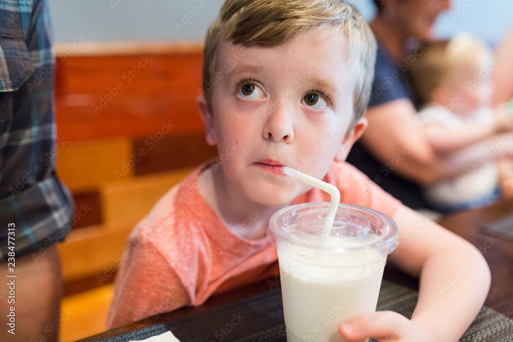Boy looking away while drinking juice on table in restaurant Boy looking away while drinking juice on table in restaurant