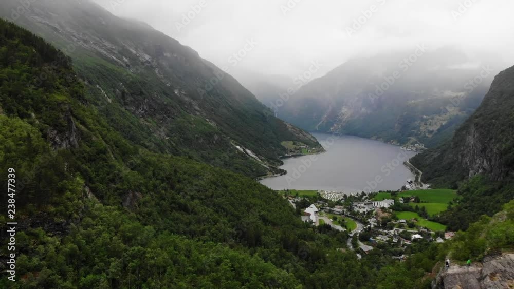 Geiranger village and fjord Geirangerfjord from Flydalsjuvet viewpoint, Norway. Evening time, overcast hazy weather. Travel destination Geiranger village and fjord Geirangerfjord from Flydalsjuvet viewpoint, Norway. Evening time, overcast hazy weather. Travel destination