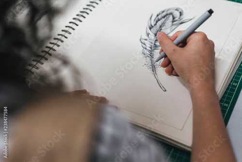 Cropped image of female artisan drawing on book in workshop photo