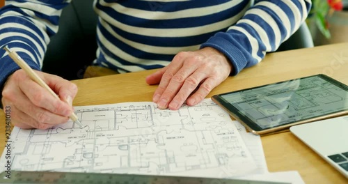 Architect Working On Construction Design Blueprints At His Desk
