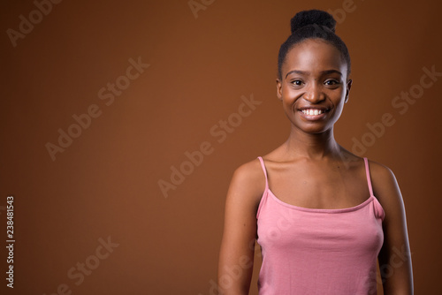 Happy African Zulu woman smiling against brown background