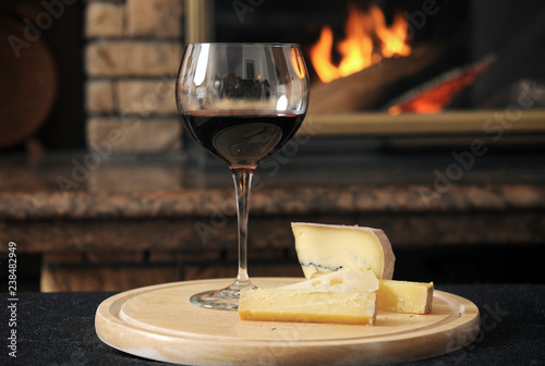 Close up of wine with cheese slices served on wooden tray