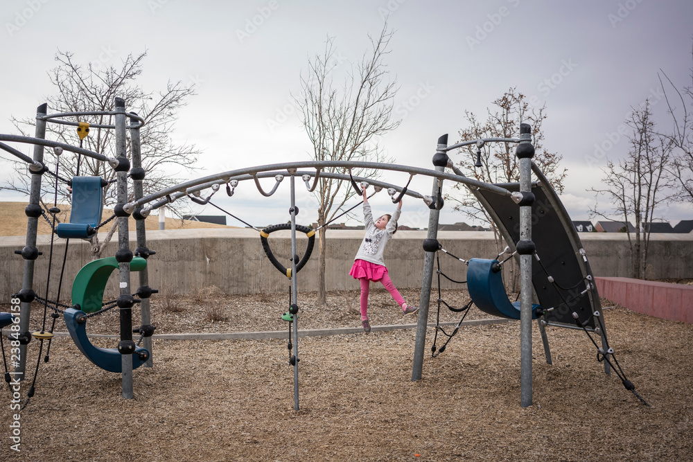 Girl hanging on monkey bars in playground Girl hanging on monkey bars in playground