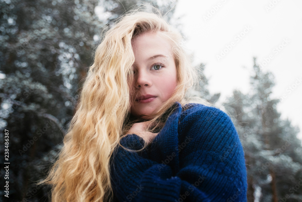 Low angle portrait of woman with blond hair standing against trees in forest during winter Low angle portrait of woman with blond hair standing against trees in forest during winter