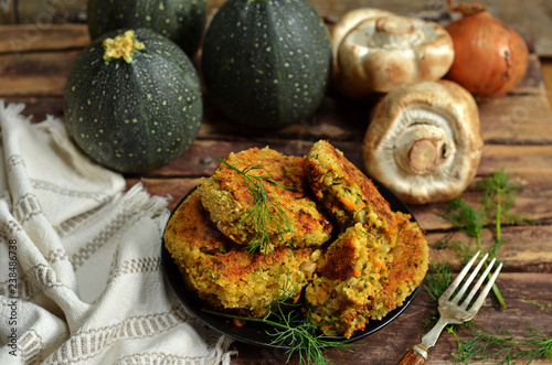 Cutlets with zucchini and mushrooms on a black saucer on a wooden background