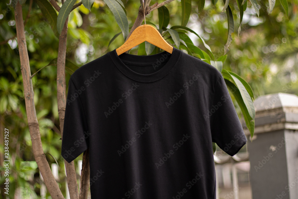 Closeup black t-shirt short sleeve on wood hanger in outdoor Closeup black t-shirt short sleeve on wood hanger in outdoor