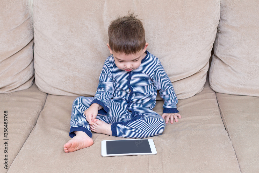 toddler boy is using a tablet on a couch toddler boy is using a tablet on a couch