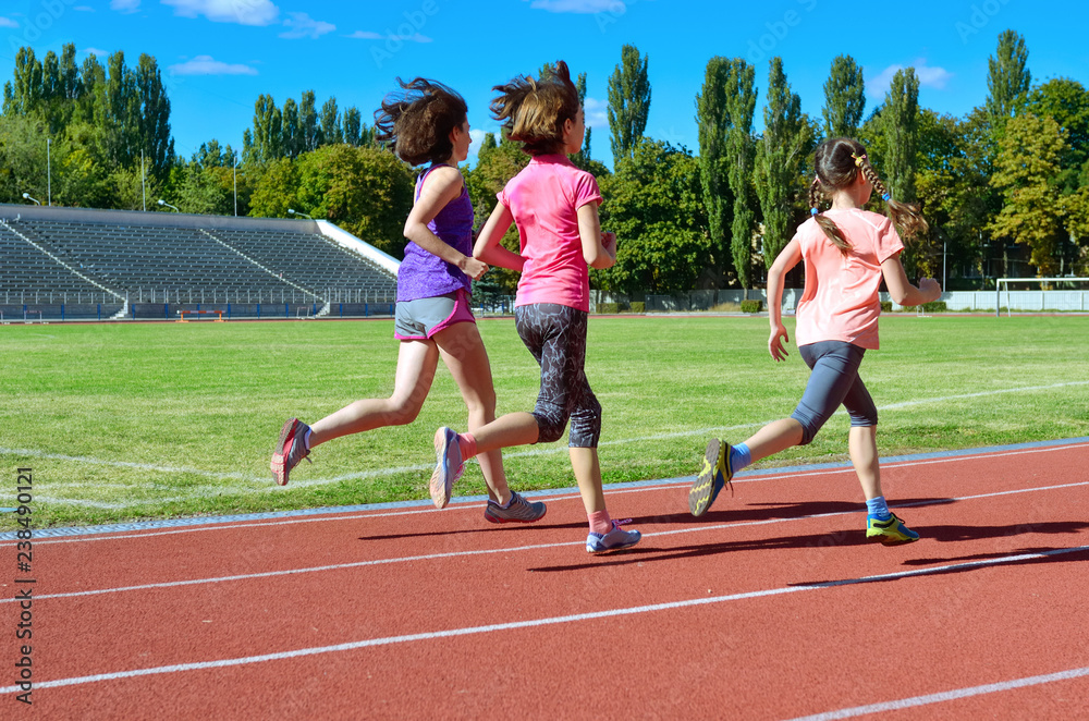 Family sport and fitness, happy mother and kids running on stadium track outdoors, children healthy active lifestyle concept
