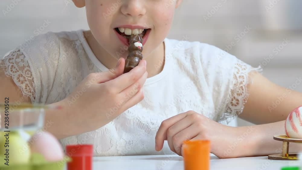 Happy little girl enjoying tasty chocolate rabbit, sweet Easter gift, childhood