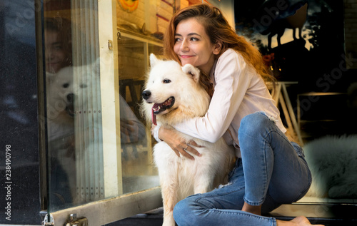 Girl with a big fluffy white dog, hugging and playing with dog