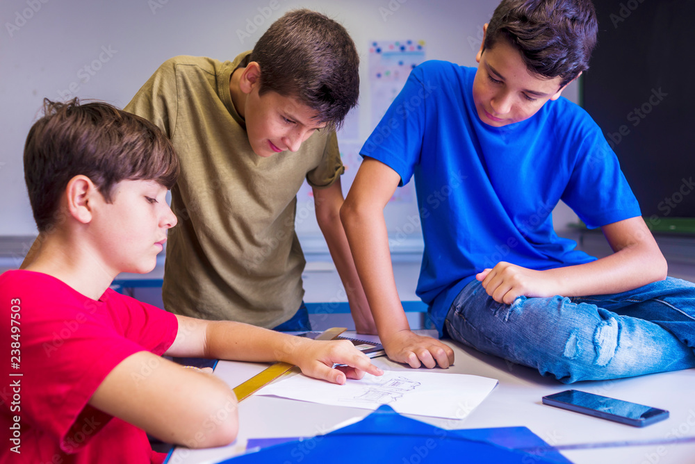 Schoolboys discussing paper in classroom Schoolboys discussing paper in classroom