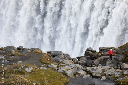 The famous Icelandic giant Dettifoss waterfall and a woman dressed in yellow in the foreground.