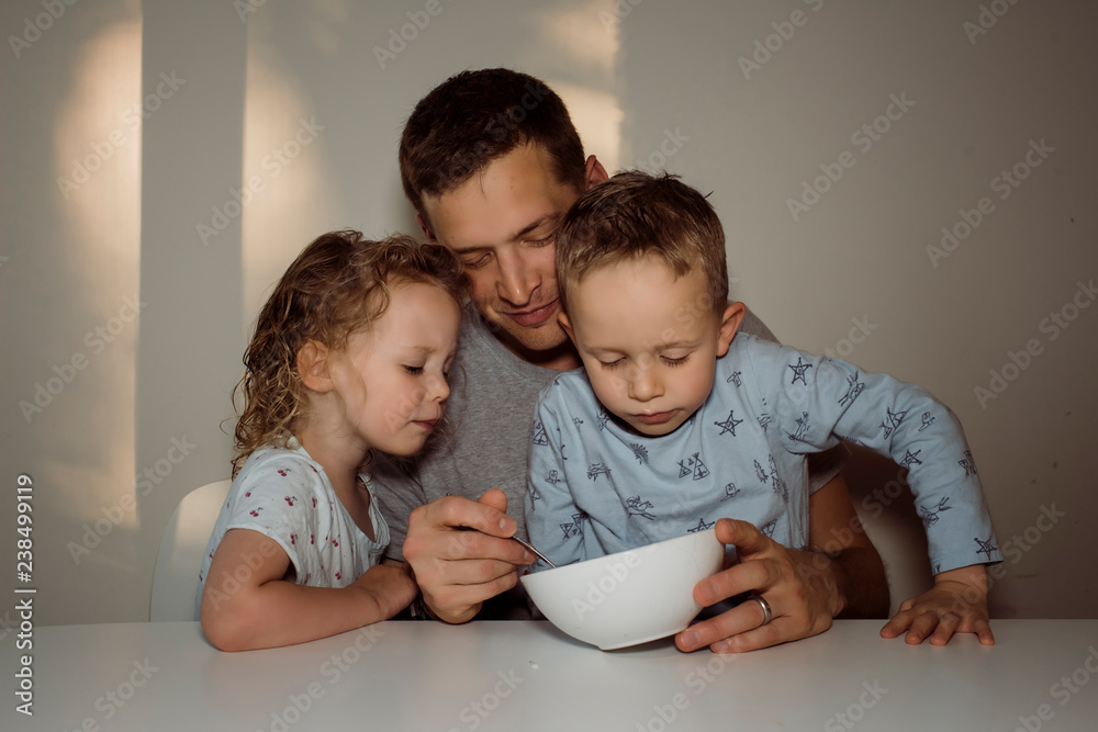Father feeding children at home Father feeding children at home
