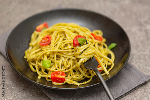 Vegetarian pasta spaghetti with basil pesto and cherry tomatoes.