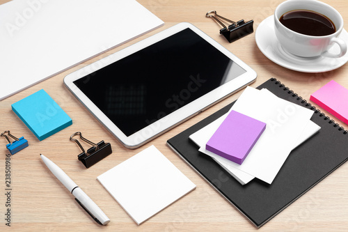 Digital tablet with notepad  supplies and coffee cup on desktop.