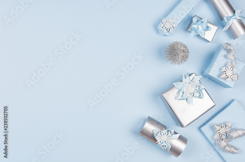 Winter festive background for advertising and design - set of blue and silver metallic gift boxes with ribbons on soft light pastel blue color backdrop, copy space.