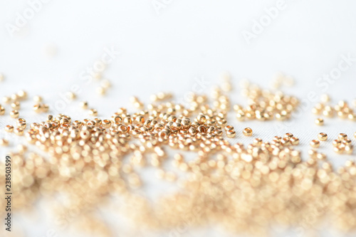 Golden seed beads scattered on textile background close up