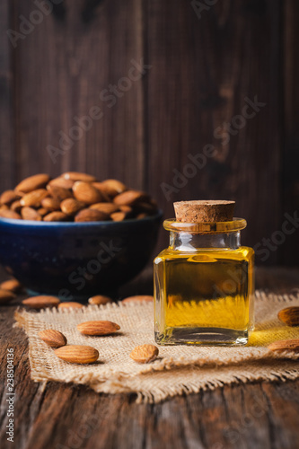 Almond oil in a little glass bottle on rustic wooden board