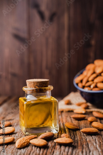 Almond oil in a little glass bottle on rustic wooden board