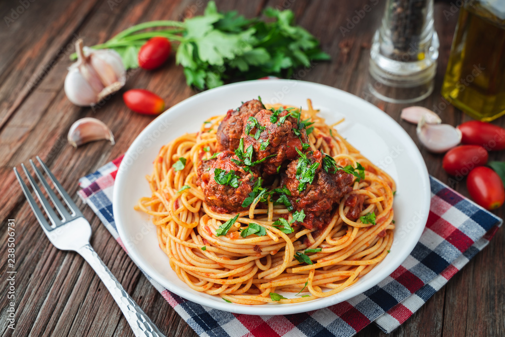 Spaghetti and meatballs with tomato sauce in white dish on wooden rustic board, Italian food closeup and top view. Spaghetti and meatballs with tomato sauce in white dish on wooden rustic board, Italian food closeup and top view.