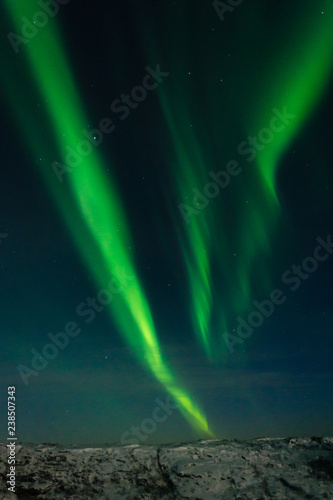 Beautiful stripes of the northern lights, aurora in the night sky above the hills.