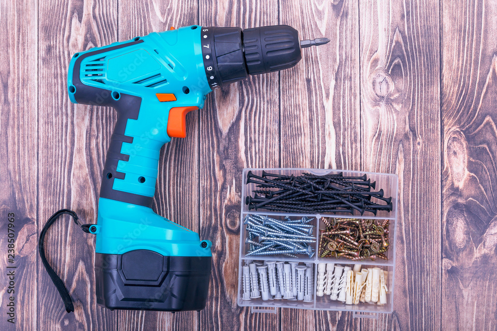 Modern rechargeable screwdriver and screws in box close up Modern rechargeable screwdriver and screws in box close up