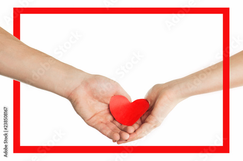 The hands of people hold a red heart in a red frame. Valentines day relationship concept. On isolated background