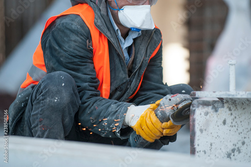 Worker cutting metal with grinder at construction site.Sparks while grinding iron