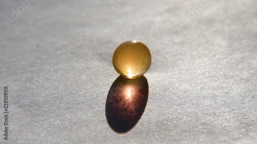 a gel bead with a gold shadow on a white background