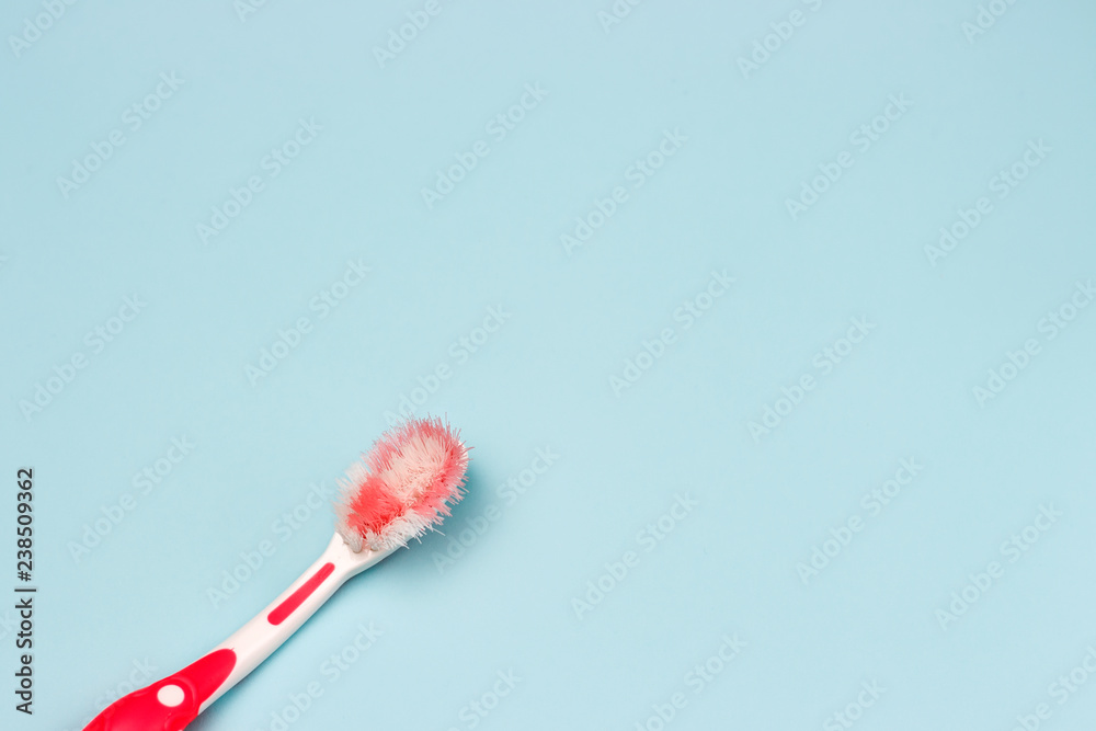 Used pink toothbrush close-up on a blue background, top view Used pink toothbrush close-up on a blue background, top view