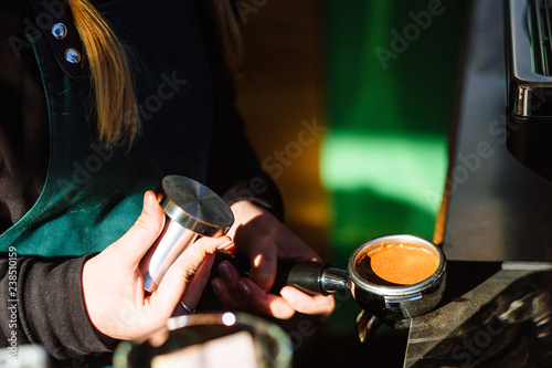 Barista presses ground coffee using tamper. Close up