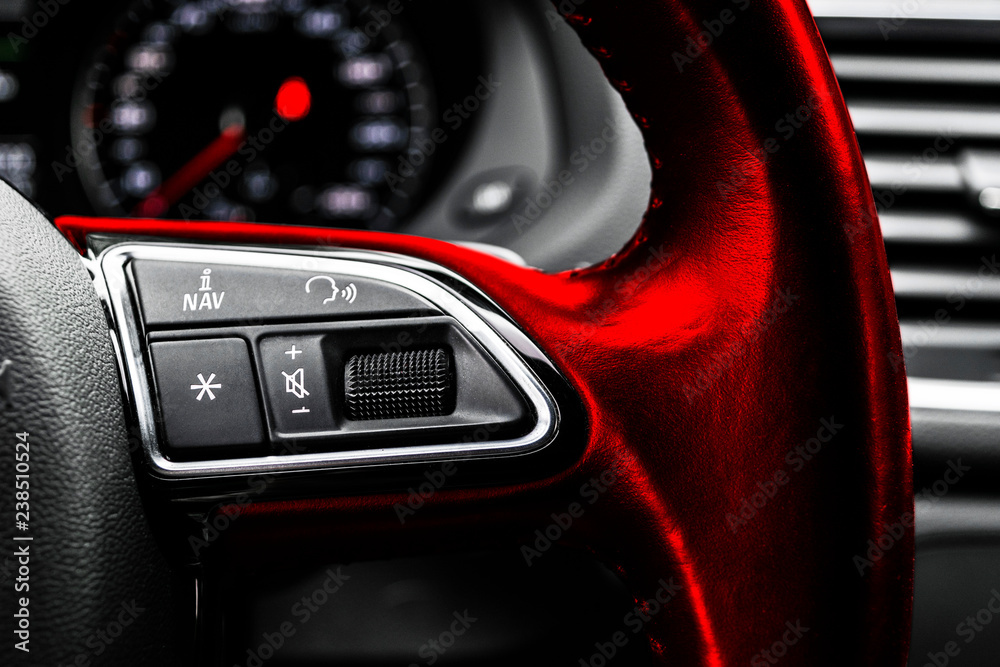 Modern car interior. Red Steering wheel with media phone control buttons, navigation multimedia system background. Car interior details. Car detailing