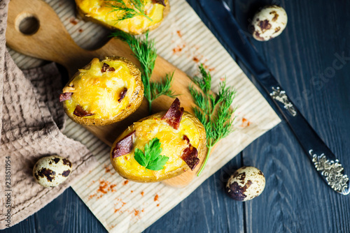 baked potato stuffed with cheese and bacon on paper on wooden background