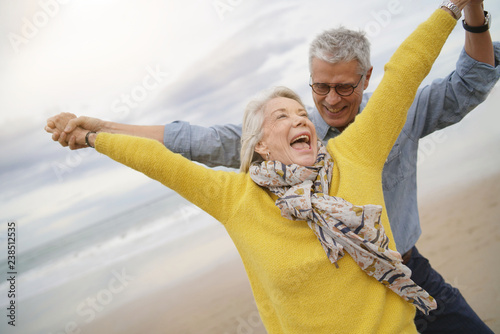 Фотография Lively senior couple playing around on beach together