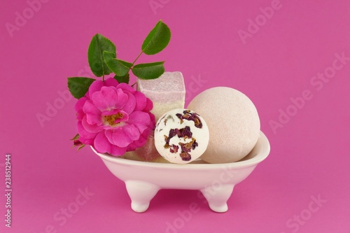 pink bath bombs set with rose extract. bath truffle, pink rose flower in a white ceramic bath on a pink background. Organic Cosmetic Spa Body Kit