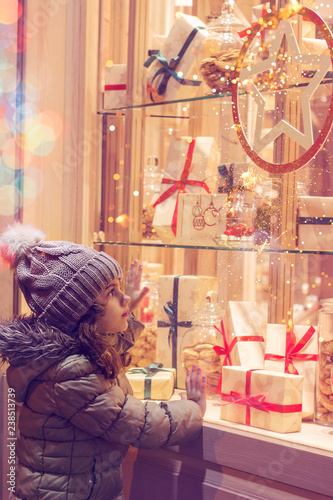 Little girl infront of window of a store, full of wrapped gifts; Christmas background
