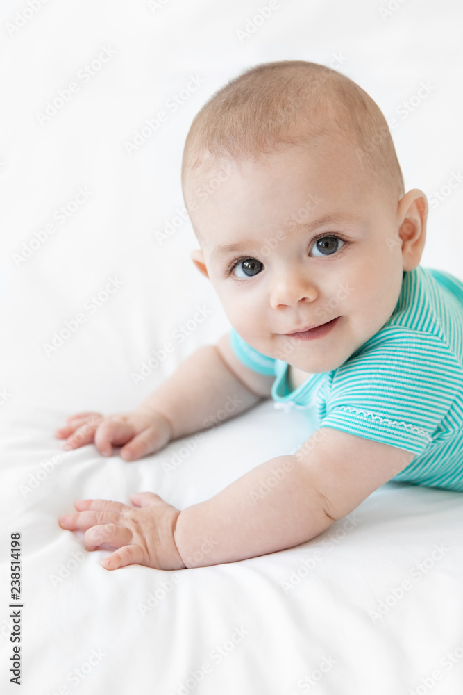 Portrait of cute baby lying on tummy on white bed Portrait of cute baby lying on tummy on white bed