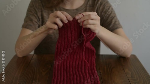Woman knitting a scarf at a wooden table