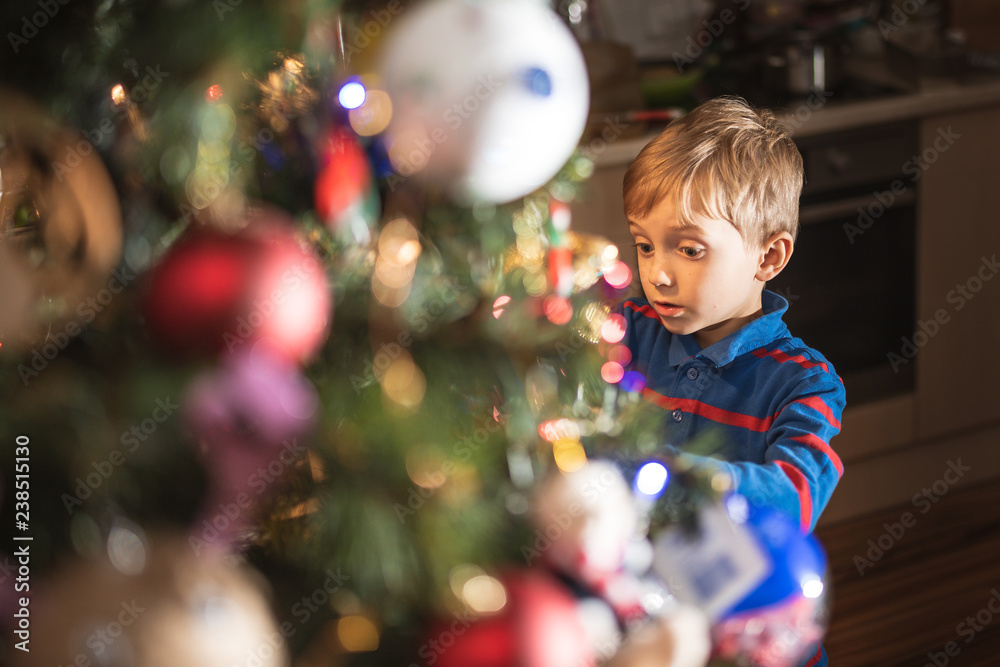 Portrait of 6 years old boy decorating Christmas tree