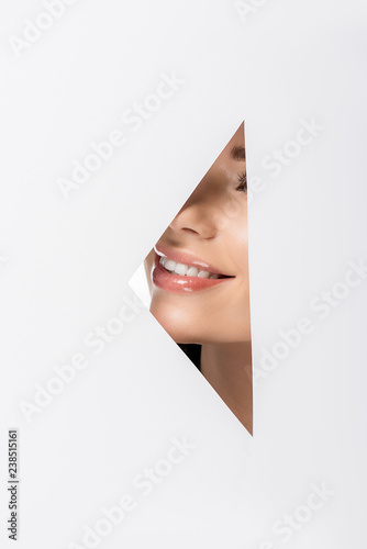 cropped shot of beautiful girl smiling through hole on white © LIGHTFIELD STUDIOS