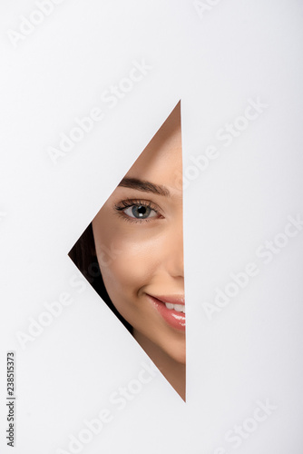 beautiful young woman smiling at camera through hole on white © LIGHTFIELD STUDIOS