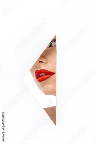 beautiful young woman red red lips looking away  view through hole on white