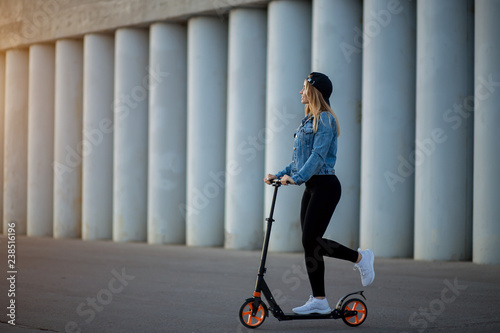 Beautiful young woman riding a scooter on the asphalt